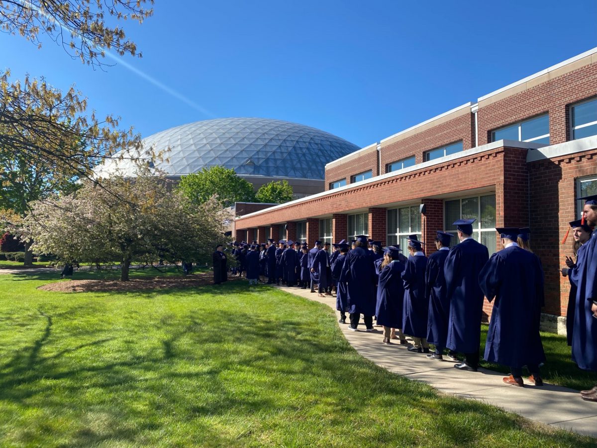 graduating students in blue cap and gowns lining up preparing for commencement ceremony in gampel