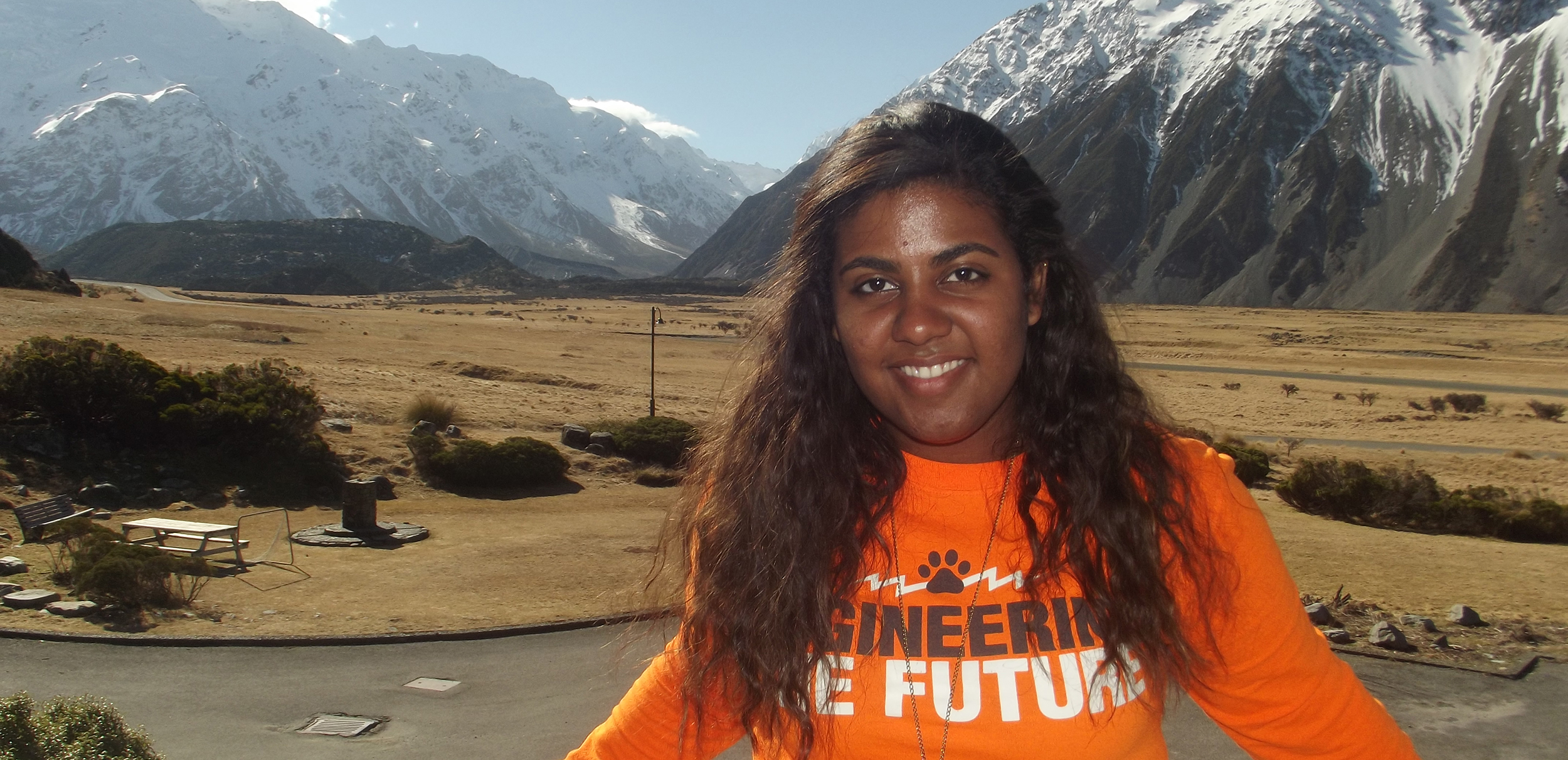 An engineering student poses for a photo in front of mountains while studying abroad.